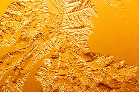 Gold patterns from frost on glass as a background. Close-up