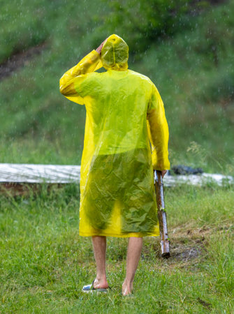 A man in a raincoat in the rain in nature.の写真素材
