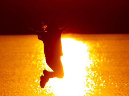 The girl jumped on the lake. Sunsetの写真素材