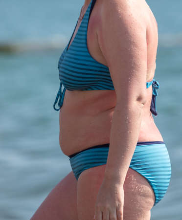 Fat woman in a swimsuit on the seashore. Rest at the resort.の写真素材