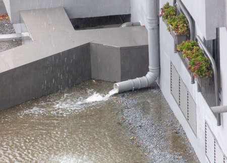 The drain near the building in the rain water. Stormの写真素材