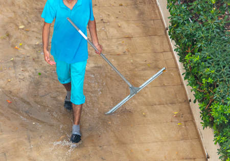 The man cleans the road after the rain.の写真素材