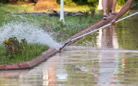 People remove water from the street after rain.