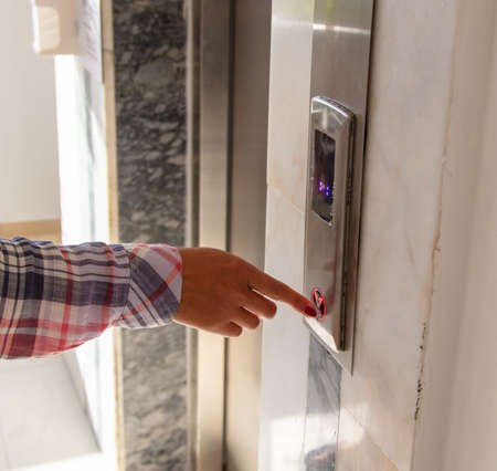 The girl presses the button of the elevator.の写真素材