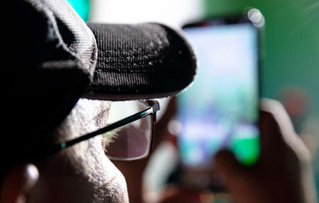 A man with glasses is filming a video on his phone. Concert at nightの写真素材