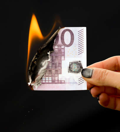 Five hundred Euros are burning with fire in hand isolated on black background.の写真素材