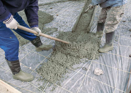 Workers level out the concrete mix at a construction site. Technologiesの写真素材