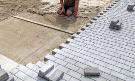 A worker lays down sand for paving slabs. Constructionの写真素材