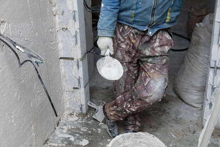 The man is plastering the walls in the house.