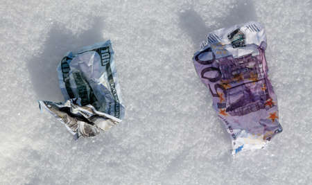 Five hundred Euros and one hundred Dollars lie in the snow. Close-upの写真素材