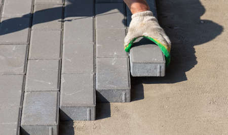 A worker lays paving slabs at a construction site.の写真素材
