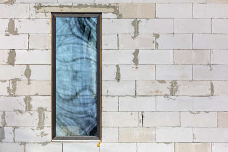 A window in a brick house under construction.