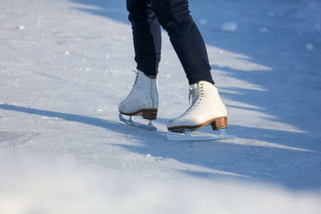 White skates on the legs of the girl on the rink.の写真素材