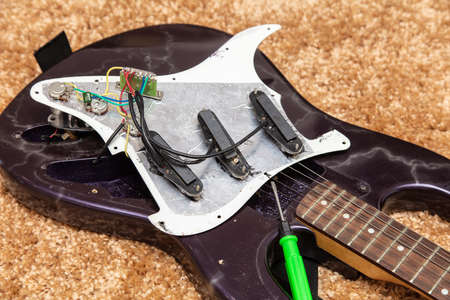 Broken electric guitar on the floor. Close-up