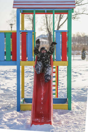 The boy is riding with a children's slide attraction on the snow in winter.の写真素材