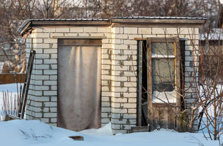 Old brick toilet in the snow in winter.の写真素材