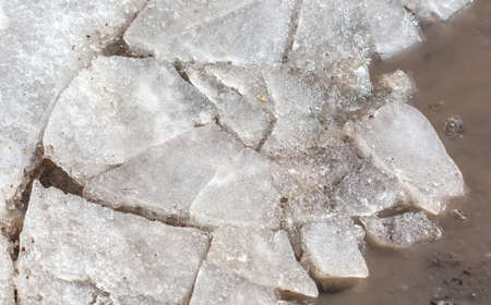 Cracked ice on a puddle as a background. Winter