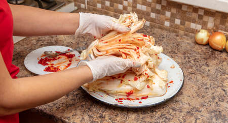 A woman is salting cabbage in Korean in the kitchen. Process