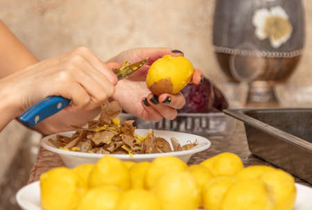 A woman peels boiled potatoes with a knife. Kitchen