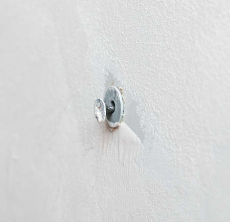 Self-tapping screw in a white wall. Close-up