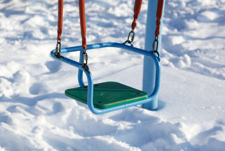 Children's swing in the snow in winter.の写真素材