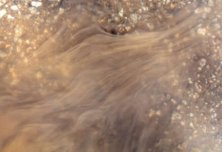 Muddy brown water in a puddle as an abstract background.