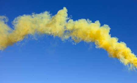 Yellow smoke on a blue sky background.の写真素材
