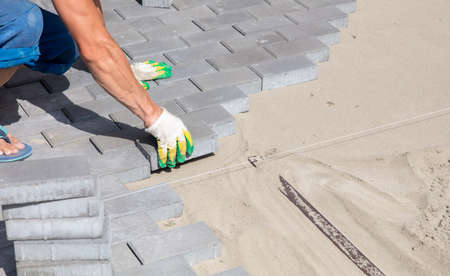 A worker is laying paving slabs in the yard.の写真素材