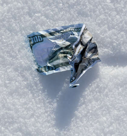 One Hundred Dollars lie in the snow. Close-upの写真素材