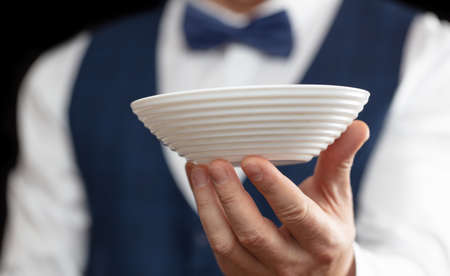 Waiter with a white plate in his hand on a black background.の写真素材