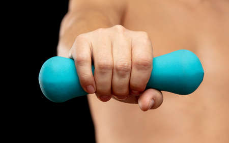 A man with a kettlebell in his hand on a black background. Sport