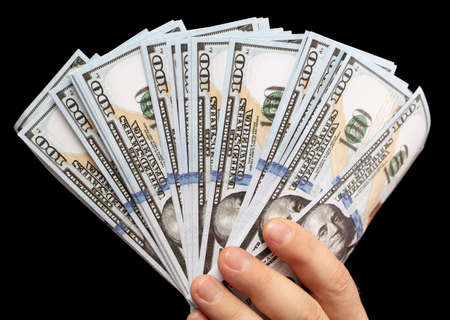 Dollars in hand isolated on black background. Close-up