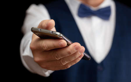 Business man with a phone in his hand on a black background.の写真素材