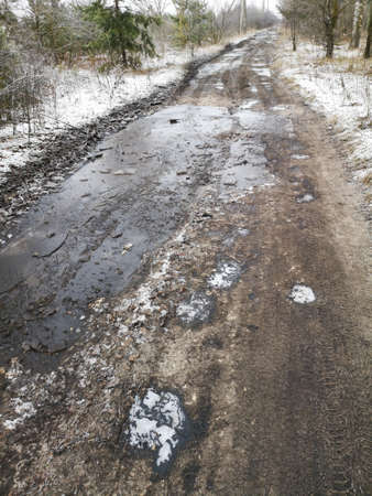 Frozen puddles on a dirt road. Nature in winterの写真素材