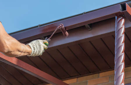 A worker paints a metal ceiling at a construction site.