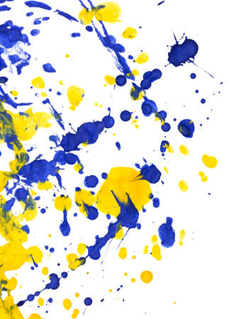 Drops of yellow and blue paint on a white paper background. Close-up
