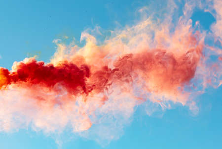 Red smoke on a blue sky background.の写真素材