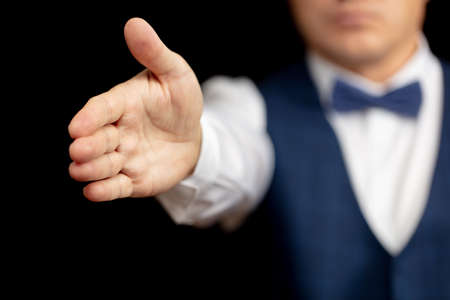 Business man extends a helping hand on a black background.の写真素材