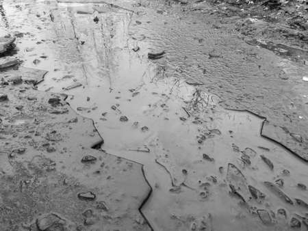 Cracked ice in a puddle. Nature in winter. Black and white photoの写真素材