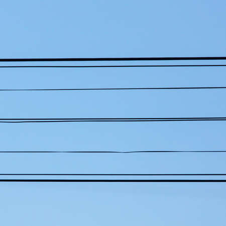 Electric wires against a blue sky.の写真素材