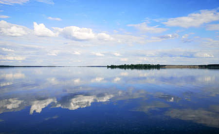 Clouds on a blue sky with reflection in water at a pond.の写真素材