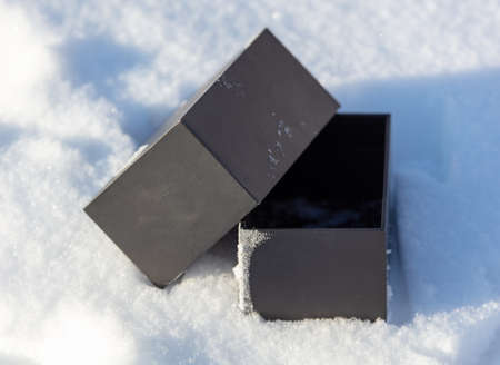 Black gift box in the snow in winter.の写真素材