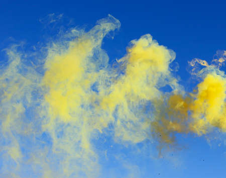 Yellow smoke on a blue sky background.の写真素材