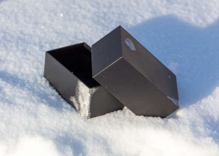Black gift box in the snow in winter.の写真素材