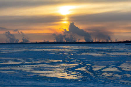 Smoke from the chimneys of a steel plant in winter at sunset.の写真素材