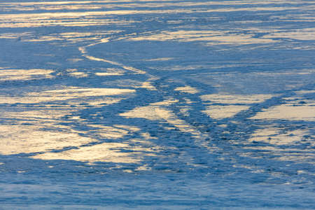 Snow on the lake in winter in the rays of sunset. background