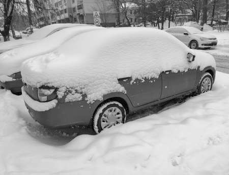 Car covered with snow near the road in winter.の写真素材
