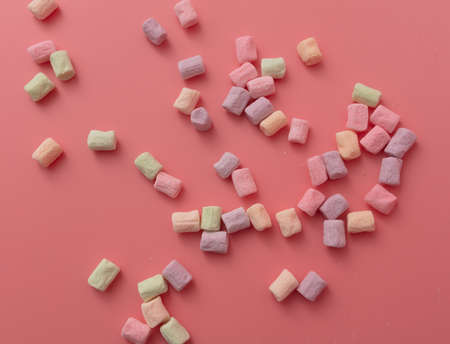 Multicolored candies on a pink background.