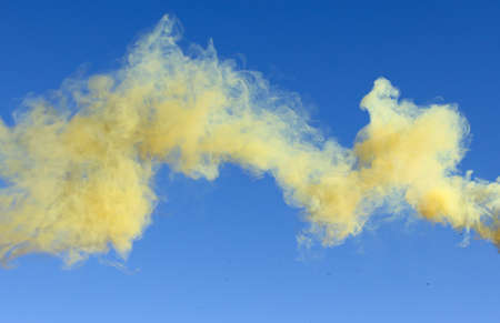 Yellow smoke on a blue sky background.の写真素材