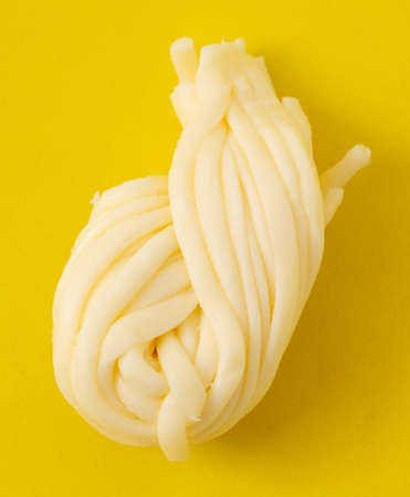 Pigtail of cheese isolated on yellow background. close-up